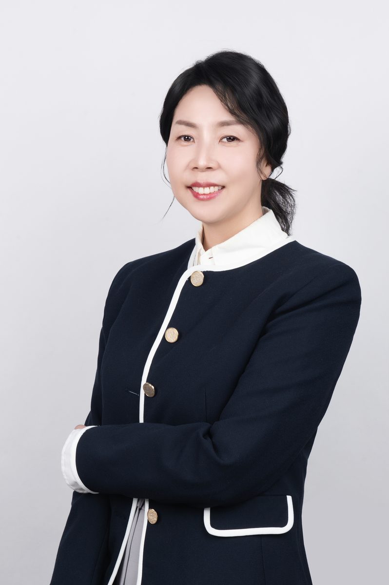 김기현 부센터장 사진-흰색 장식이 있는 짙은색 재킷을 입고 있다. 머리를 뒤로 묶고 팔짱을 낀 채 정면을 바라보며 밝게 미소 짓고 있다.